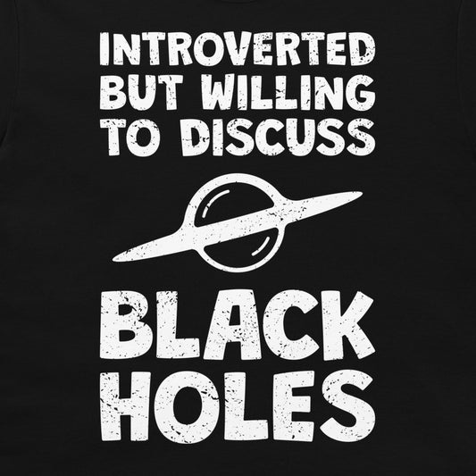 A close-up of a black graphic print featuring the distressed white text 'INTROVERTED BUT WILLING TO DISCUSS BLACK HOLES' and a white ringed planet illustration.