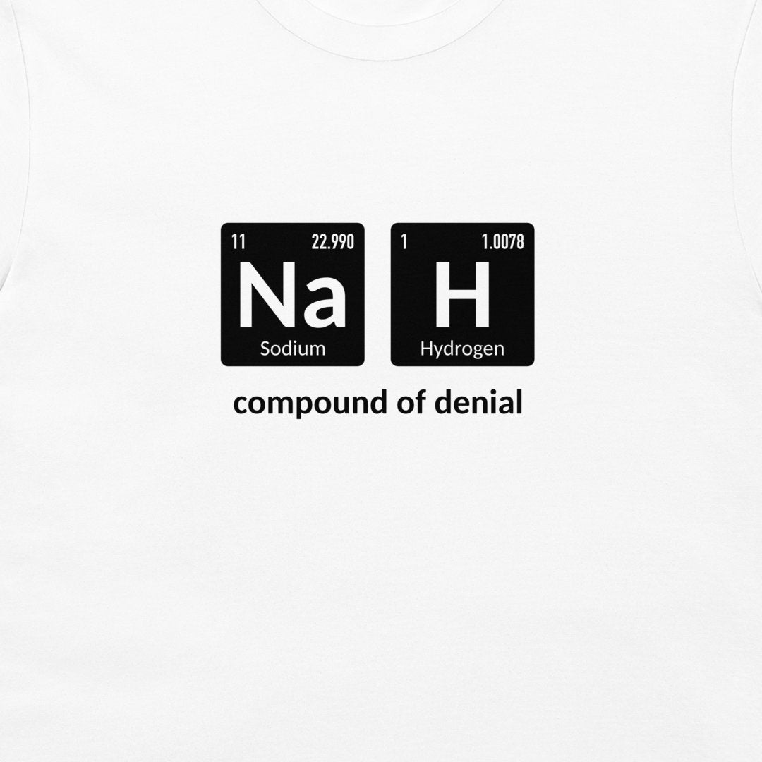 A white crewneck t-shirt featuring a graphic print of two black periodic table style tiles spelling out 'Na' and 'H' with the text 'compound of denial' underneath.