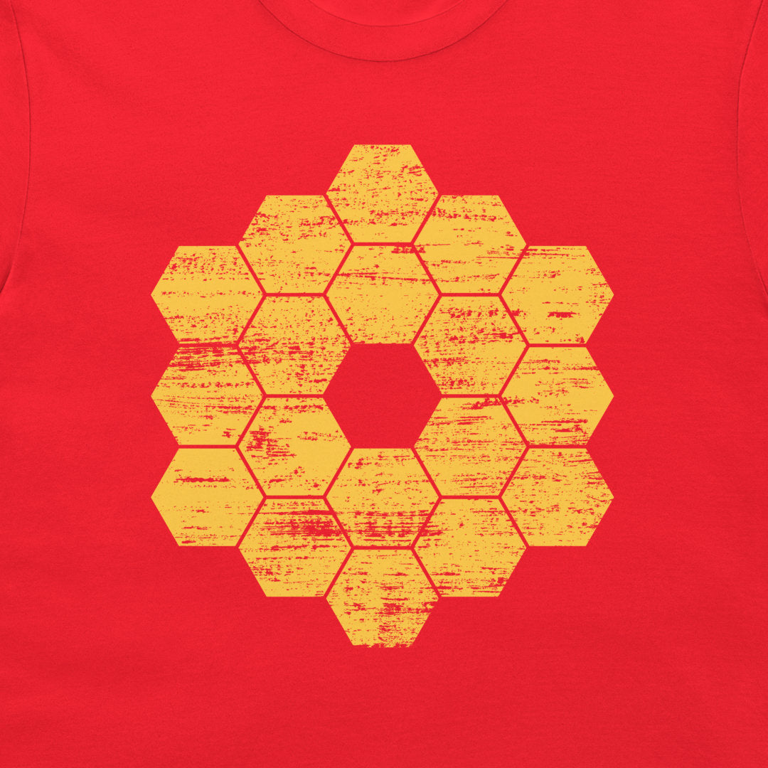 A close-up of a red garment, likely a t-shirt, featuring a distressed yellow-orange geometric honeycomb hexagon pattern printed on the chest.