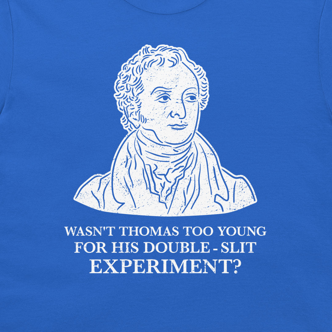 A close-up of a blue t-shirt featuring a white graphic print of a historical portrait of Thomas Jefferson with the text 'WASN'T THOMAS TOO YOUNG FOR HIS DOUBLE - SLIT EXPERIMENT?' printed below.