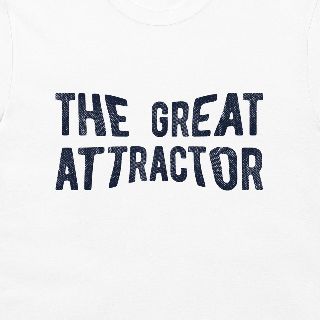 White t-shirt featuring the phrase 'THE GREAT ATTRACTOR' printed in a dark navy blue textured font across the chest.