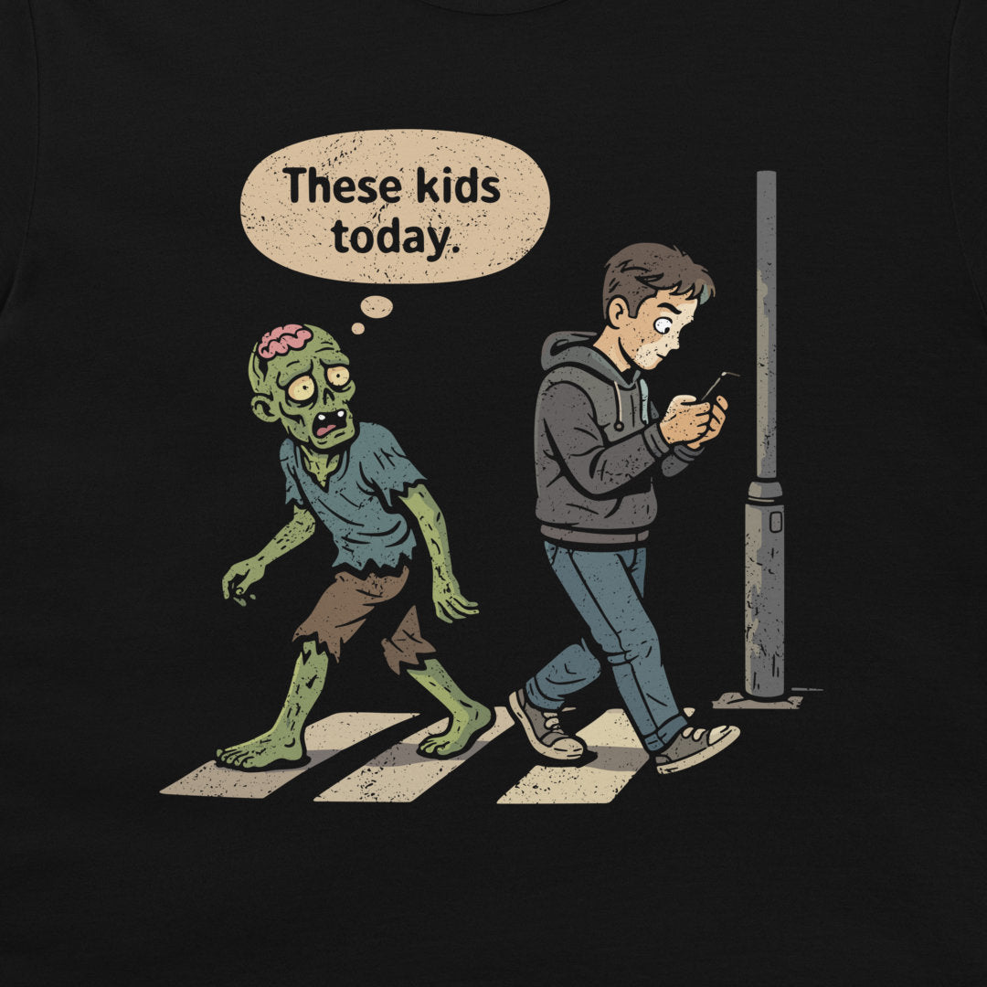 A black graphic t-shirt featuring a cartoon illustration of a zombie crossing a street while a young man looks at his phone. A speech bubble above the zombie reads, 'These kids today'.