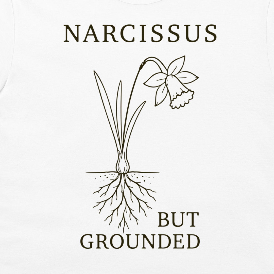 A white t-shirt featuring a dark brown graphic of a narcissus flower with its roots exposed, accompanied by the text 'NARCISSUS BUT GROUNDED'.
