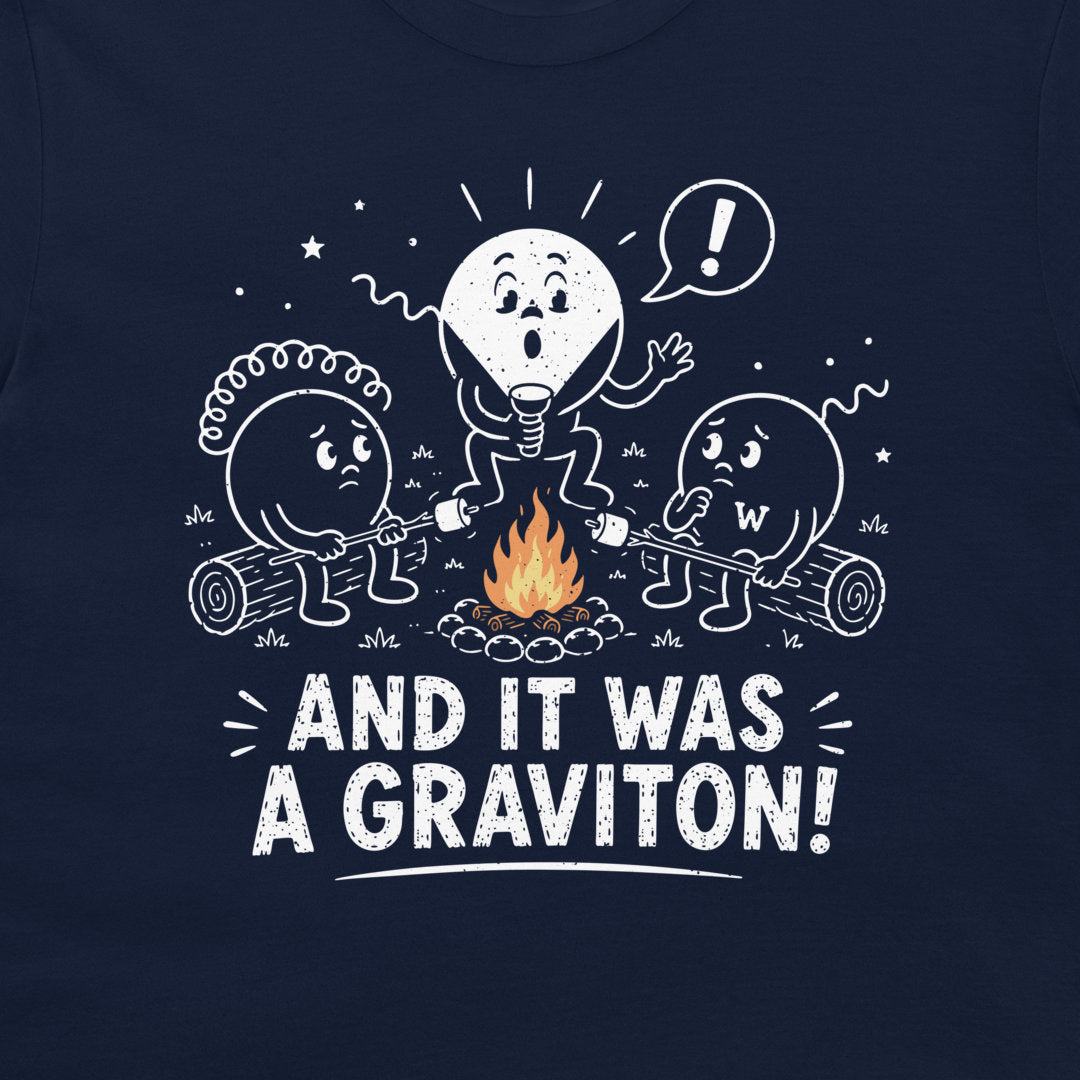 A close-up of a navy blue t-shirt featuring a white graphic of three cartoon particle characters roasting marshmallows over a campfire, with the text 'AND IT WAS A GRAVITON!' printed below.