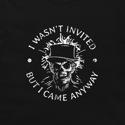 A close-up of a black garment featuring a distressed white graphic print of a skull wearing a top hat, surrounded by the text 'I WASN'T INVITED BUT I CAME ANYWAY'.