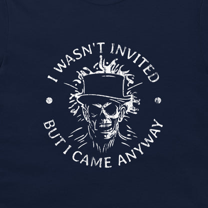 A close-up of a navy blue t-shirt, featuring a distressed white graphic print of a skull in a top hat with flames, surrounded by the text 'I WASN'T INVITED BUT I CAME ANYWAY'.
