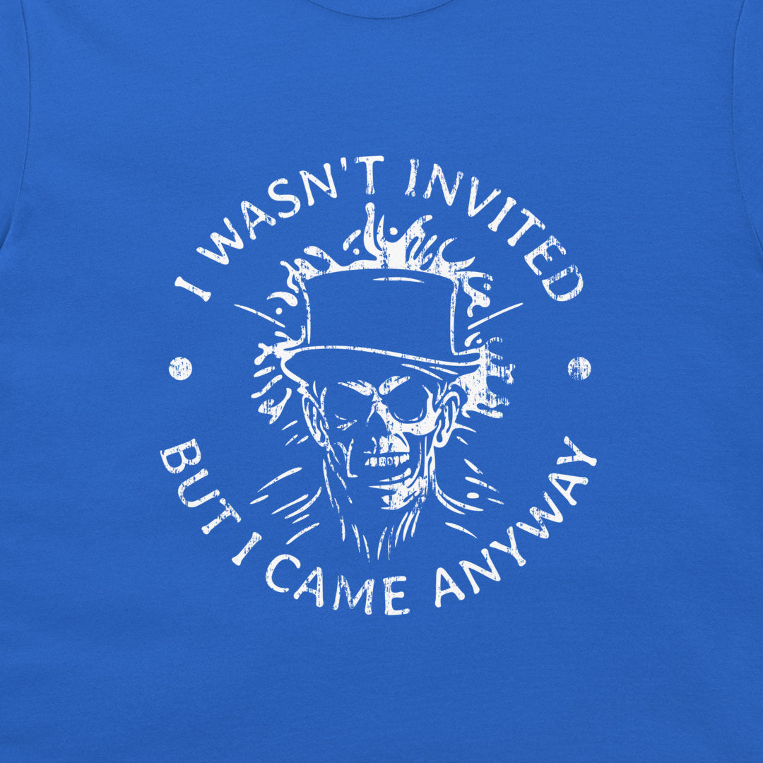 A close-up of a royal blue t-shirt featuring a distressed white graphic of a skull in a top hat with the text 'I WASN'T INVITED BUT I CAME ANYWAY'.