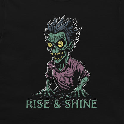 A black t-shirt featuring a graphic of a green zombie with yellow eyes, wild hair, and a purple shirt, with the text 'RISE & SHINE' written below in a distressed teal font.