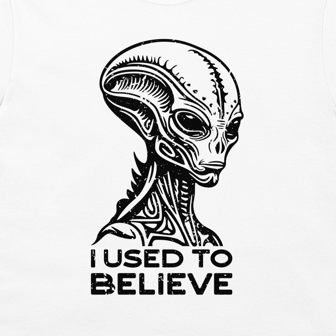 A white t-shirt featuring a black graphic of a stylized alien head with the text 'I USED TO BELIEVE' printed below it.