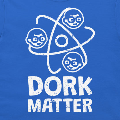A close-up of a blue T-shirt featuring a white distressed graphic of three cartoon faces orbiting a circle, with the text 'DORK MATTER' printed below.