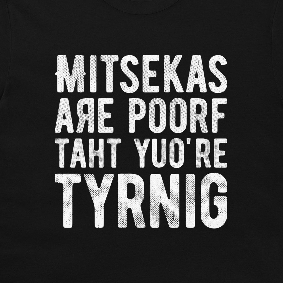 A close-up of a black t-shirt featuring a humorous text graphic in distressed white capital letters that reads 'MITSEKAS ARE POORF TAHT YU'O RE TYRNIG'.