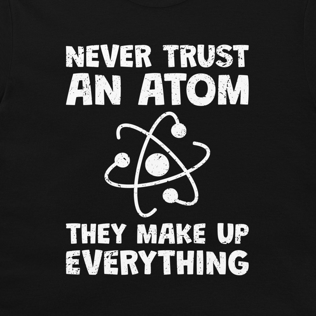A close-up of a black garment, likely a t-shirt, featuring a white distressed graphic print that reads 'NEVER TRUST AN ATOM THEY MAKE UP EVERYTHING' with an atom symbol in the center.