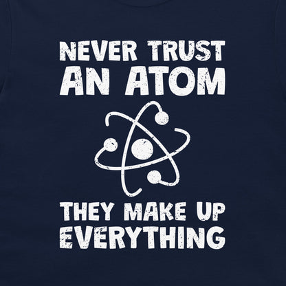 A close-up of a navy blue garment, likely a t-shirt, featuring a white distressed graphic print that reads 'NEVER TRUST AN ATOM THEY MAKE UP EVERYTHING' with an atom symbol in the center.