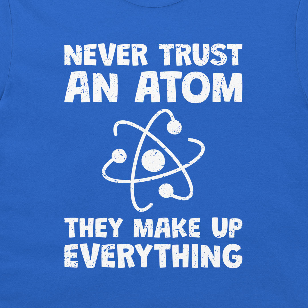 A close-up of a blue T-shirt or sweatshirt featuring a white distressed graphic that reads 'NEVER TRUST AN ATOM THEY MAKE UP EVERYTHING' with an atom symbol in the center.