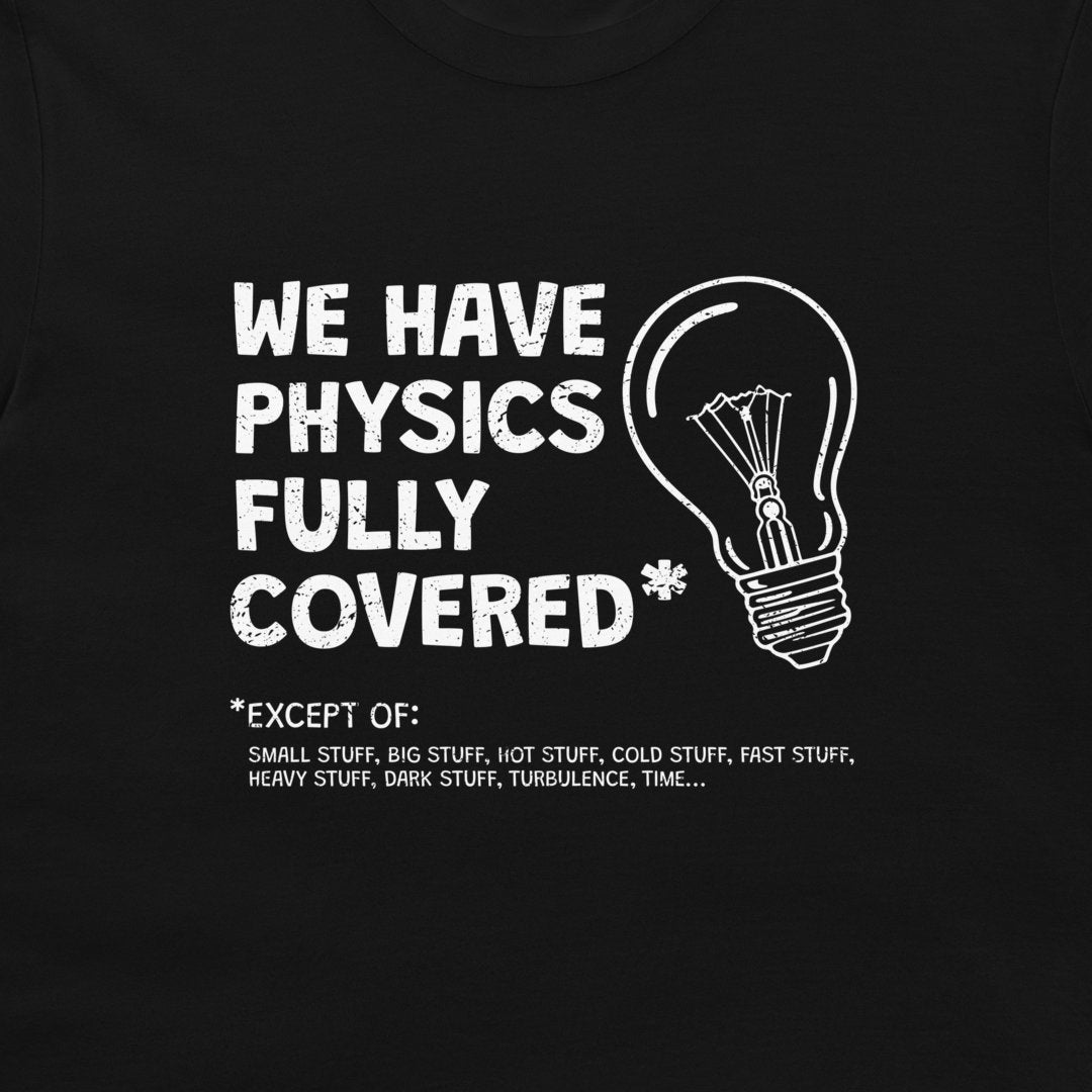 A close-up of a black t-shirt featuring a white graphic print that reads 'WE HAVE PHYSICS FULLY COVERED' next to a hand-drawn light bulb, with a humorous exception list printed below.