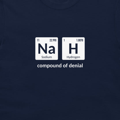 A close-up of a navy blue t-shirt featuring a white graphic print that reinterprets the periodic table elements 'Na' (Sodium) and 'H' (Hydrogen) as the 'compound of denial'.