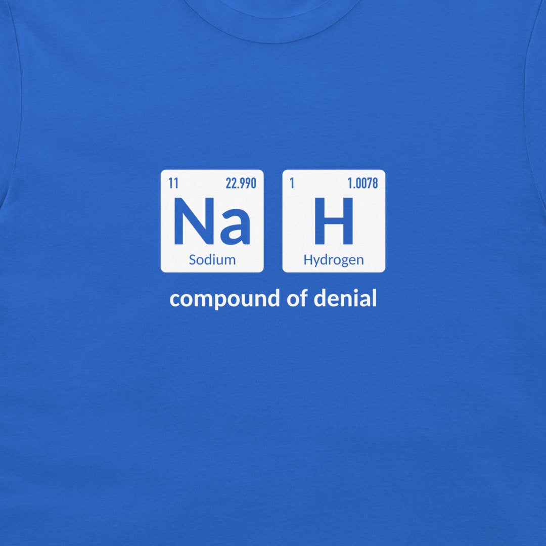 A close-up of a bright blue t-shirt featuring a graphic print of the periodic table elements Sodium (Na) and Hydrogen (H) arranged to spell 'NaH', with the text 'compound of denial' printed below in white.