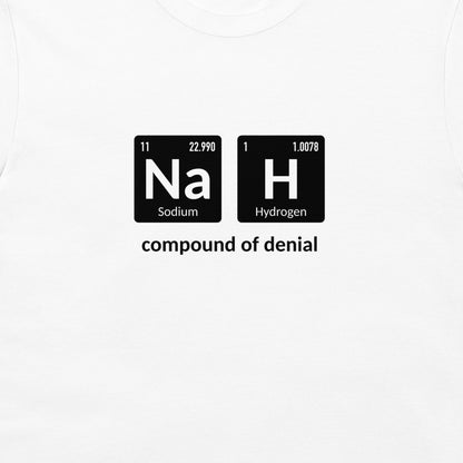 A white crewneck t-shirt featuring a graphic print of two black periodic table style tiles spelling out 'Na' and 'H' with the text 'compound of denial' underneath.