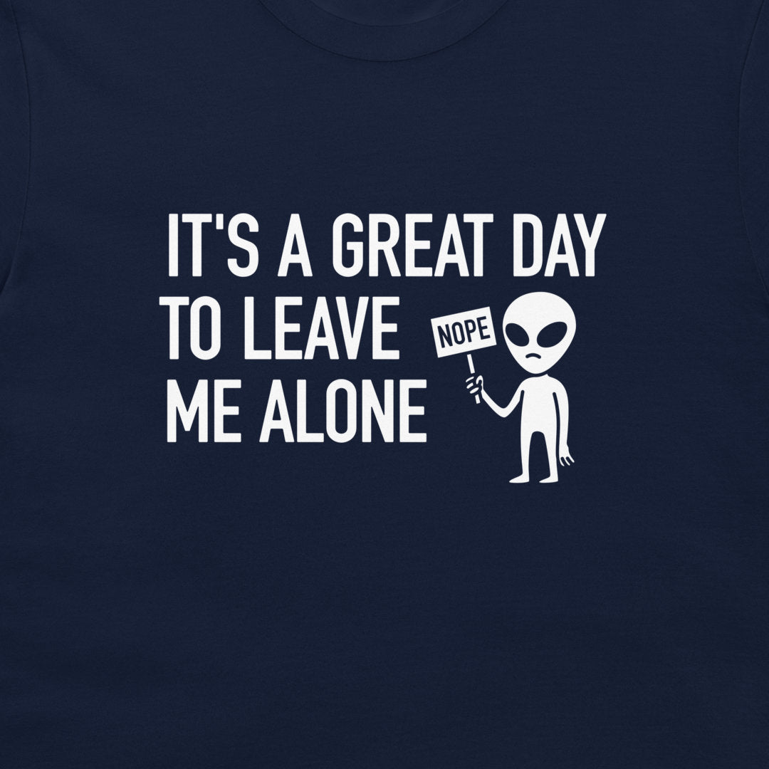 A close-up of a navy blue t-shirt featuring a white graphic print that reads 'IT'S A GREAT DAY TO LEAVE ME ALONE' next to a cartoon alien holding a 'NOPE' sign.