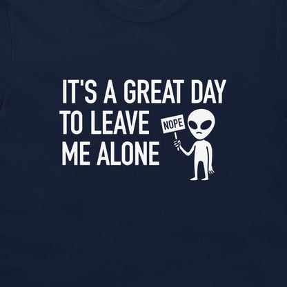 A close-up of a navy blue t-shirt featuring a white graphic print that reads 'IT'S A GREAT DAY TO LEAVE ME ALONE' next to a cartoon alien holding a 'NOPE' sign.