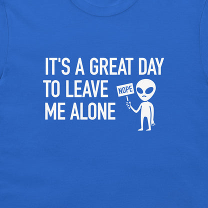 A close-up of a royal blue t-shirt featuring a white graphic print that reads 'IT'S A GREAT DAY TO LEAVE ME ALONE' next to a cartoon alien holding a 'NOPE' sign.