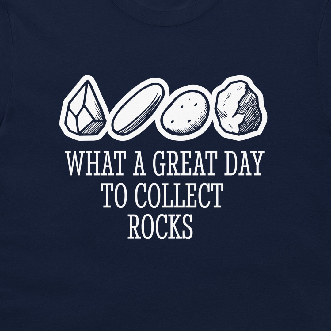 A close-up of a navy blue t-shirt featuring a white graphic print of four different rocks and crystals above the text 'WHAT A GREAT DAY TO COLLECT ROCKS'.