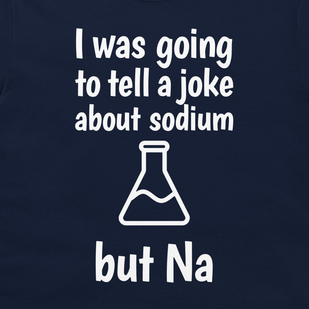 A close-up of a navy blue t-shirt, featuring a white graphic print that reads 'I was going to tell a joke about sodium but Na' with a simple beaker outline.