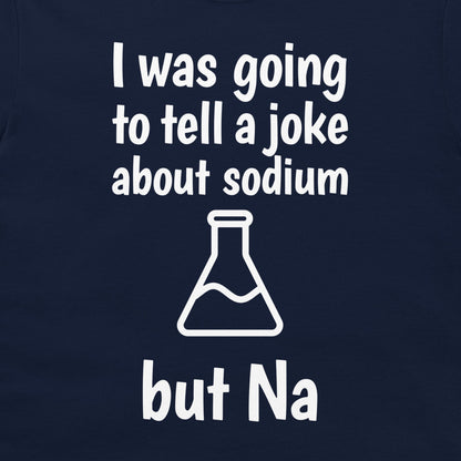 A close-up of a navy blue t-shirt, featuring a white graphic print that reads 'I was going to tell a joke about sodium but Na' with a simple beaker outline.
