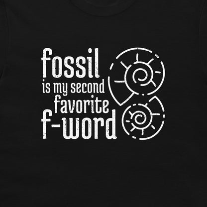 A close-up of a black t-shirt featuring a white distressed graphic that reads 'fossil is my second favorite f-word' alongside two spiral ammonite illustrations.