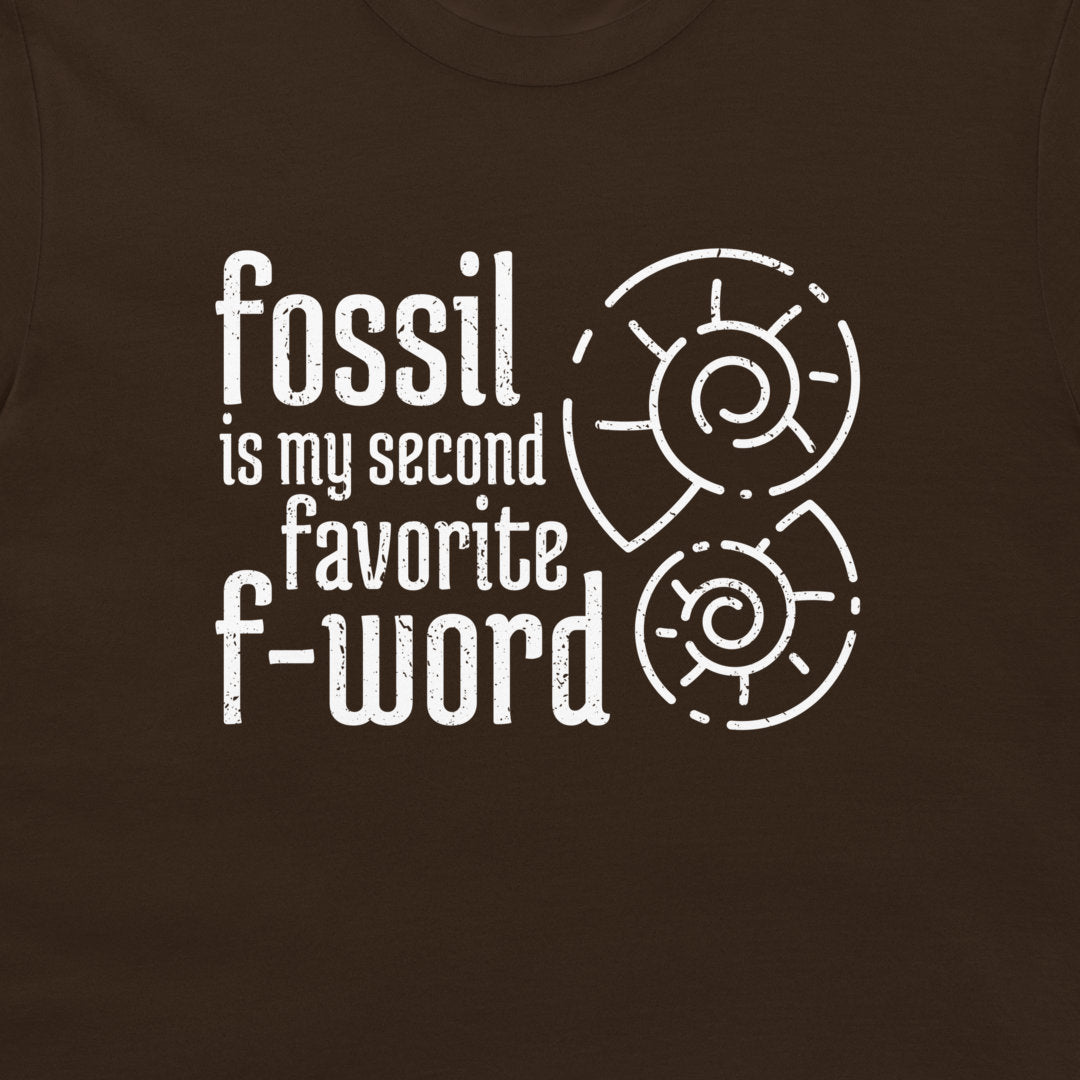 A close-up of a dark brown t-shirt featuring a white graphic print that reads 'fossil is my second favorite f-word' alongside two white spiral ammonite illustrations.