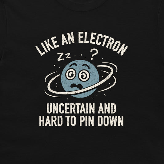 A close-up of a black t-shirt featuring a graphic print of a blue planet with a ring around it, looking confused, with the text 'LIKE AN ELECTRON' above and 'UNCERTAIN AND HARD TO PIN DOWN' below in distressed white lettering.