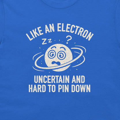 A close-up of a blue T-shirt featuring a white distressed graphic of a confused planet with a ring and the text 'LIKE AN ELECTRON UNCERTAIN AND HARD TO PIN DOWN' with 'zz' and a question mark.