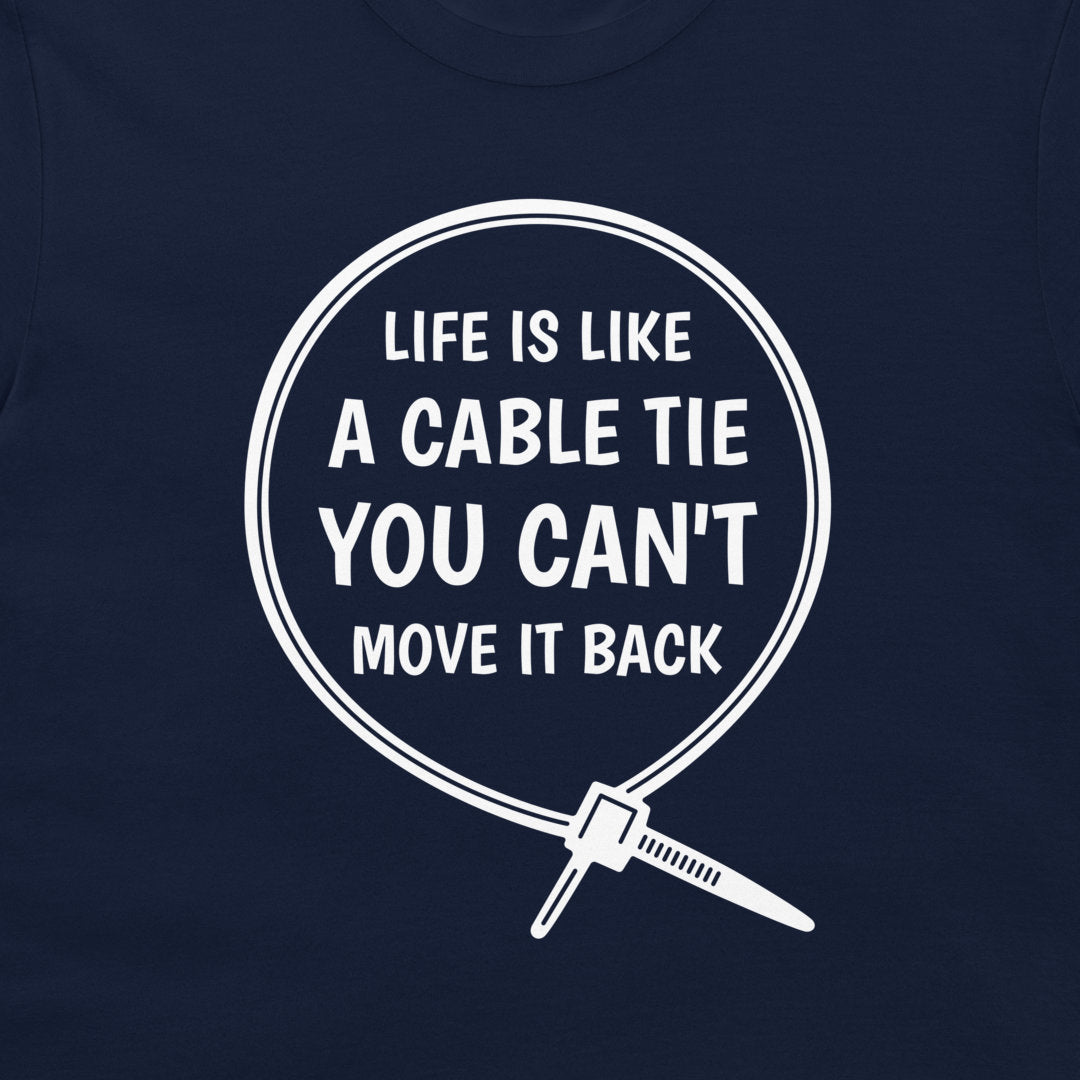 A close-up of a navy blue t-shirt, featuring a white graphic print of a cable tie inside a circle with the humorous quote 'LIFE IS LIKE A CABLE TIE YOU CAN'T MOVE IT BACK'.