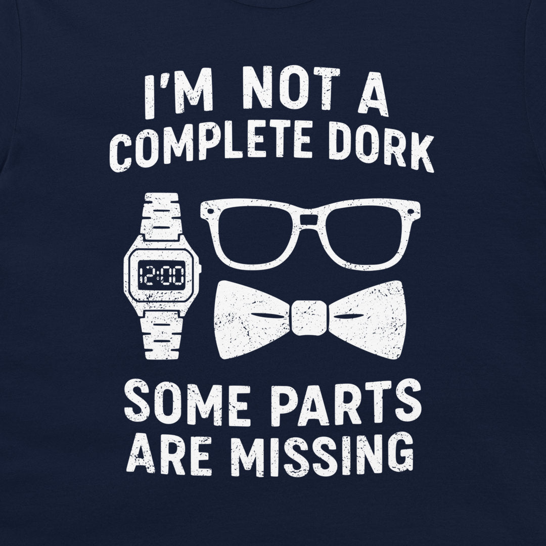 A close-up of a navy blue shirt featuring a white distressed graphic that reads 'I'M NOT A COMPLETE DORK SOME PARTS ARE MISSING' with illustrations of a digital watch, eyeglasses, and a bow tie.