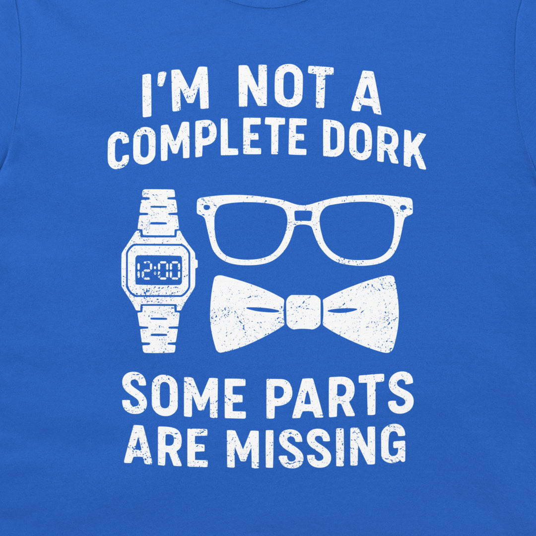 A close-up of a royal blue t-shirt featuring a white distressed graphic that reads 'I'M NOT A COMPLETE DORK SOME PARTS ARE MISSING' with illustrations of a digital watch, eyeglasses, and a bow tie.