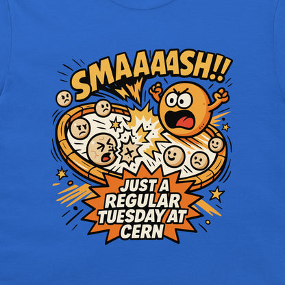 A close-up of a blue T-shirt featuring a colorful cartoon graphic of a pizza exploding with expressive faces and comic-style text reading 'SMAAAASH!!' and 'JUST A REGULAR TUESDAY AT CERN'.