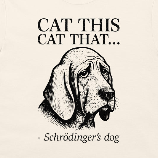 A close-up of a cream-colored t-shirt, featuring a black graphic print of a sad bloodhound Schrödinger's dog with the text 'CAT THIS CAT THAT.