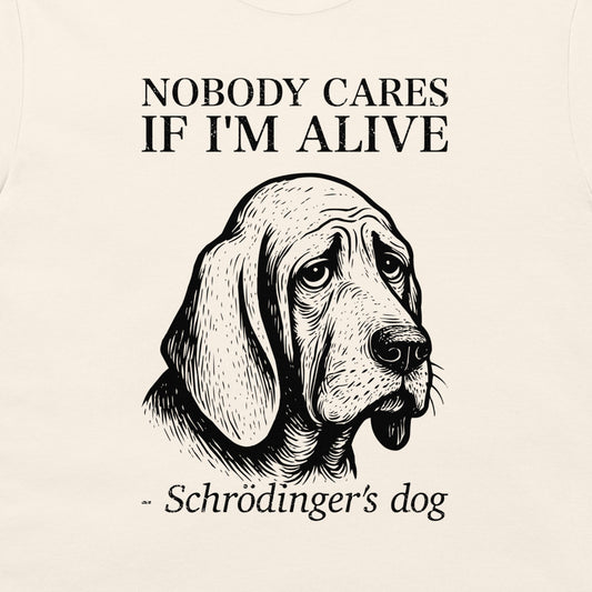A close-up of a cream-colored t-shirt featuring a black graphic print of a sad-looking bloodhound dog with the text 'NOBODY CARES IF I'M ALIVE' and '- Schrödinger's dog'.