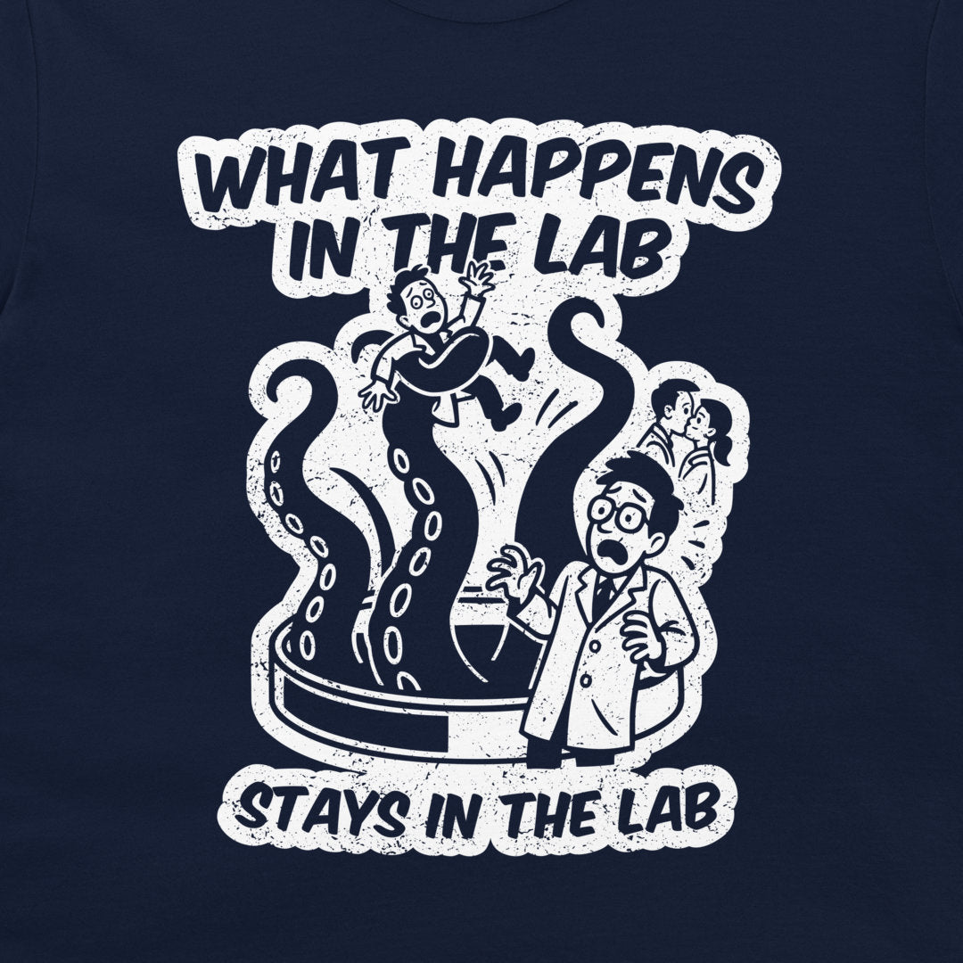 A navy blue t-shirt featuring a white distressed graphic print with the text 'WHAT HAPPENS IN THE LAB STAYS IN THE LAB' and a cartoon illustration of a lab accident.