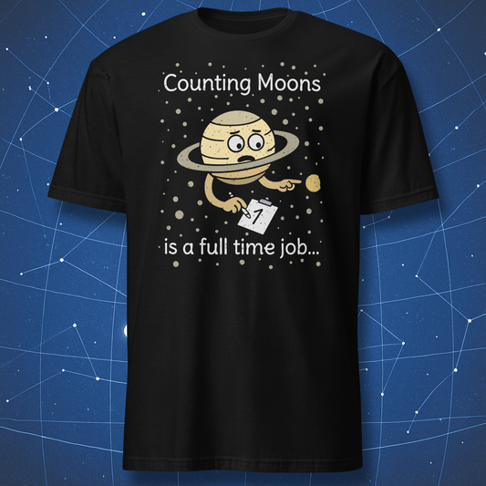 Black T-shirt with a cartoon Saturn holding a notepad and counting moons, surrounded by stars — text reads “Counting Moons is a full time job.”