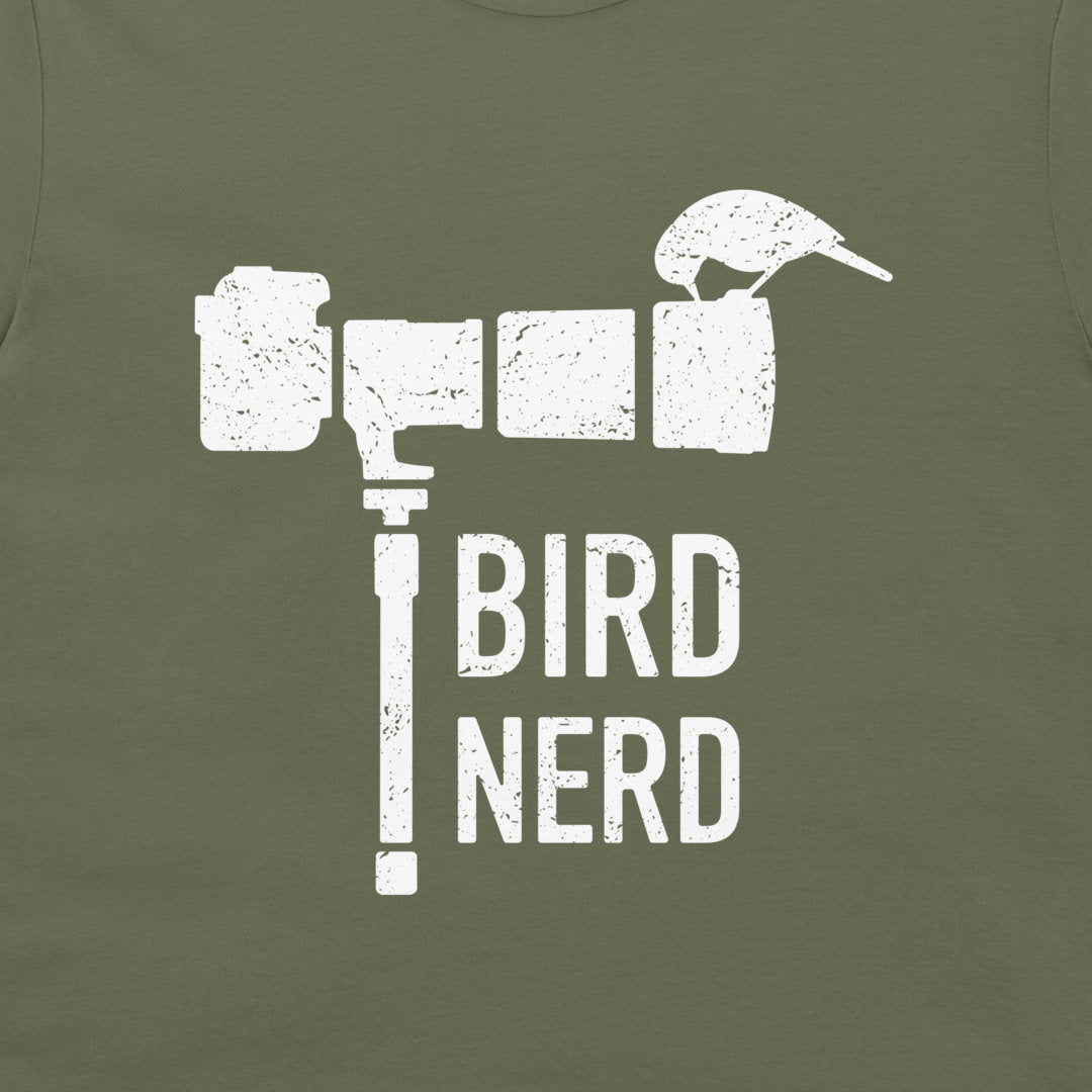 An olive green t-shirt featuring a distressed white graphic of a bird perched on a camera lens with the text 'BIRD NERD' printed below.