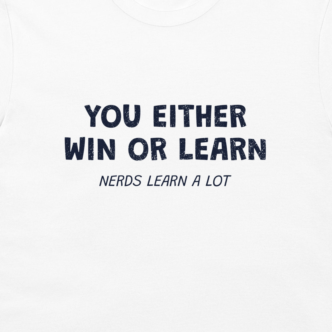A close-up of a white t-shirt featuring a navy blue  printed graphic that reads 'YOU EITHER WIN OR LEARN' with 'NERDS LEARN A LOT' underneath.