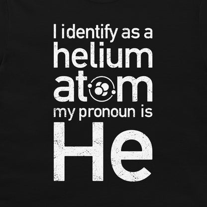 A close-up of a black t-shirt, featuring a humorous slogan printed in distressed white text: 'I identify as a helium atom my pronoun is He'.