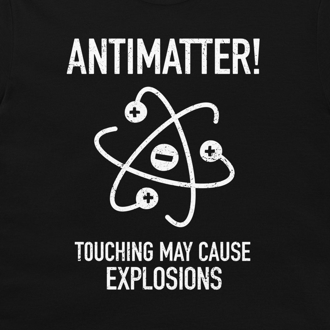 A close-up of a black t-shirt, featuring a white distressed graphic of an atom with plus and minus signs and the text 'ANTIMATTER! TOUCHING MAY CAUSE EXPLOSIONS'.