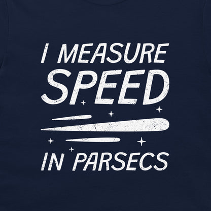 A close-up of a navy blue t-shirt, featuring a distressed white graphic print that reads 'I MEASURE SPEED IN PARSECS' with a stylized streak and star design.