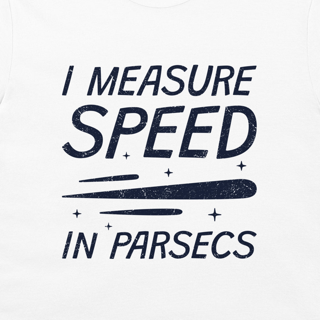 White t-shirt featuring a dark navy blue distressed graphic that reads 'I MEASURE SPEED IN PARSECS' with a stylized streak and star accents.