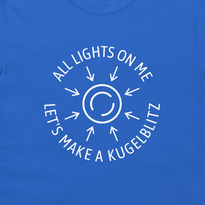 A close-up of a royal blue t-shirt featuring a white graphic print of a sun with rays and the text 'ALL LIGHTS ON ME LET'S MAKE A KUGELBLITZ'.