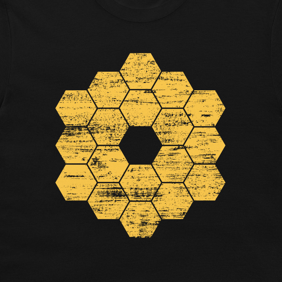 A close-up of a black garment, likely a t-shirt, featuring a distressed yellow honeycomb hexagon graphic in the center.