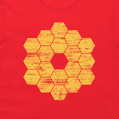 A close-up of a red garment, likely a t-shirt, featuring a distressed yellow-orange geometric honeycomb hexagon pattern printed on the chest.