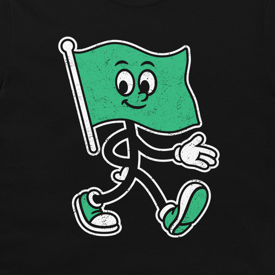 A black t-shirt featuring a distressed graphic of a walking green flag character with a smiling face, white stick figure limbs, and green-and-white sneakers.